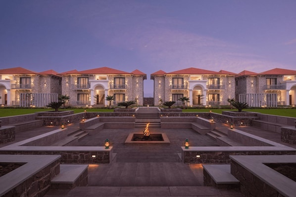 A hotel with a symmetrical facade, stone exterior, and a central courtyard with a fire feature. - Bookmark Resort Jogi Mahal Ranthambore (Sawai Madhopur)