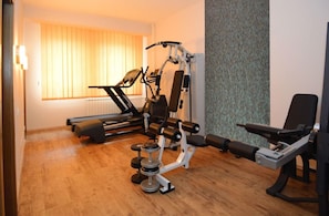 Un gimnasio en casa con cinta de correr, banco de pesas y equipo de ejercicio variado.