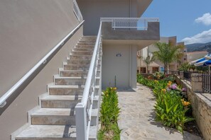 A staircase leading to a building with a balcony, surrounded by a garden with various plants and flowers. - Amara Seaside (Hersonissos)