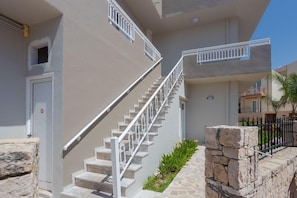 A multi-story building with a staircase, stone walls, and a metal railing. - Amara Seaside (Hersonissos)