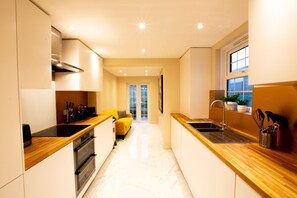 A modern kitchen with built-in appliances, a wooden countertop, and a view to a balcony. - Charles Hope Apartments Salisbury Residences (Salisbury)