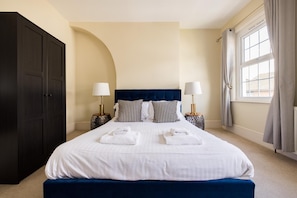 A hotel room with a large bed, two bedside lamps, a wardrobe, and a window with curtains. - Charles Hope Apartments Salisbury Residences (Salisbury)
