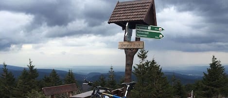A mountain viewpoint with a directional signpost, a bicycle, and a bench.