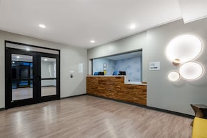 A reception area with a wooden reception desk, a glass partition, and a sign indicating 'Manager On Duty'. - Echo Suites Extended Stay by Wyndham Nashville/ Gallatin (Spartanburg)