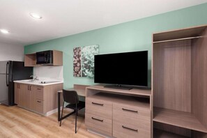 A modern kitchen with a built-in microwave, a flat-screen TV, and a wooden cabinet. - Echo Suites Extended Stay by Wyndham Nashville/ Gallatin (Spartanburg)