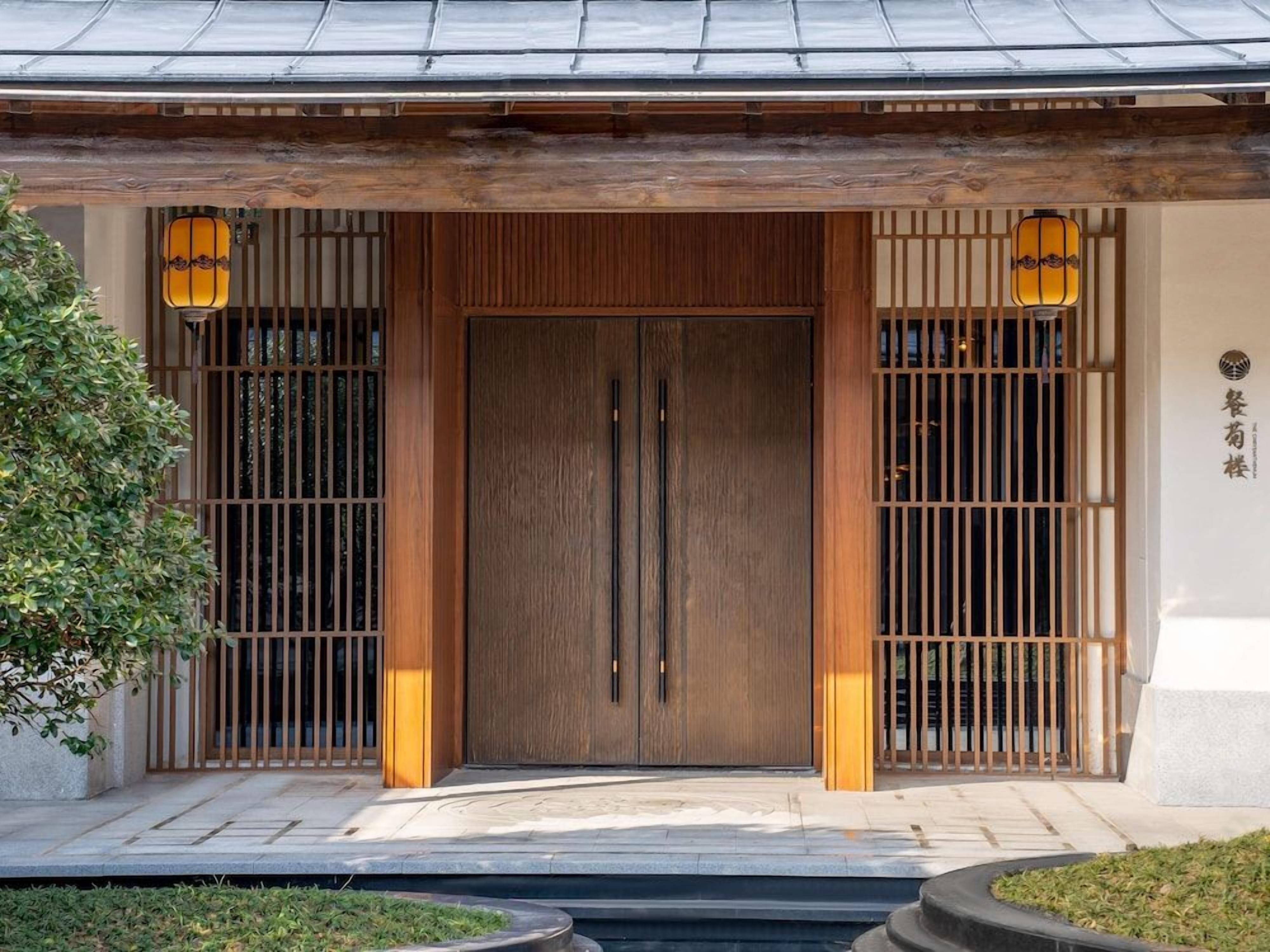 A traditional Japanese building entrance with a wooden door, sliding panels, and lanterns.