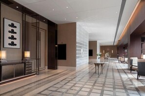 A modern hotel lobby with a marble floor, a reception desk, seating area, and a decorative wall. - Dangkou Ancient Town Hotel Wuxi - Mgallery Collection (Suzhou)