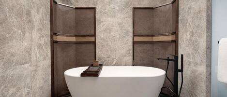 A modern bathroom with a freestanding bathtub, marble walls, and a tiled floor.