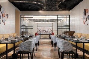 A restaurant with a central dining table surrounded by chairs, a patterned wall, and a ceiling with a unique design. - Dangkou Ancient Town Hotel Wuxi - Mgallery Collection (Suzhou)