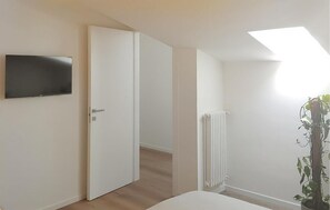 A bedroom with a bed, a TV mounted on the wall, a radiator, and a door leading to another room. - 1 bedroom stunning apartment in Salò (Salò)
