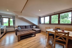A modern living room with a sectional sofa, wooden coffee table, and a dining table with chairs. - Pension Alpenblick Holiday Apartment Obadob (Oy-Mittelberg OT Maria-Rain)