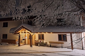 A snow-covered building with a covered entrance and a bench outside. - Pension Alpenblick Holiday Apartment Obadob (Oy-Mittelberg OT Maria-Rain)