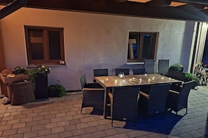 An outdoor patio with a wooden table and chairs, potted plants, and a brick floor. - Pension Alpenblick Holiday Apartment Obadob (Oy-Mittelberg OT Maria-Rain)