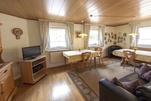 A cozy living room with a television, a dining table, and a sofa. - Holiday apartment with 3 bedrooms (Impflingen)