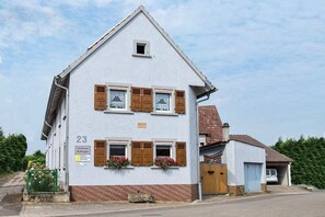 A two-story building with a gabled roof, numbered 23, featuring wooden shutters, flower boxes, and a small window. - Holiday apartment with 3 bedrooms (Impflingen)