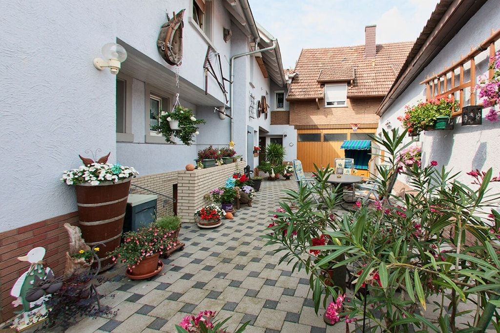 A courtyard with potted plants, a wooden table, and a blue awning.