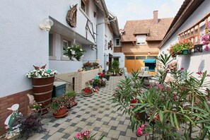A courtyard with potted plants, a wooden table, and a blue awning. - Holiday apartment with 3 bedrooms (Impflingen)