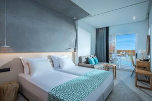 Habitación de hotel con una cama grande, un sofá, una mesita y vistas a una piscina.