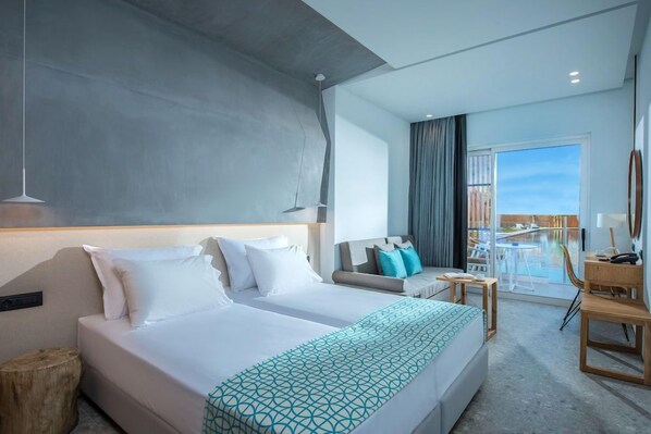 A hotel room with a large bed, a sofa, a small table, and a view of a pool. - Sensus Experience By Lavris Group (Hersonissos)