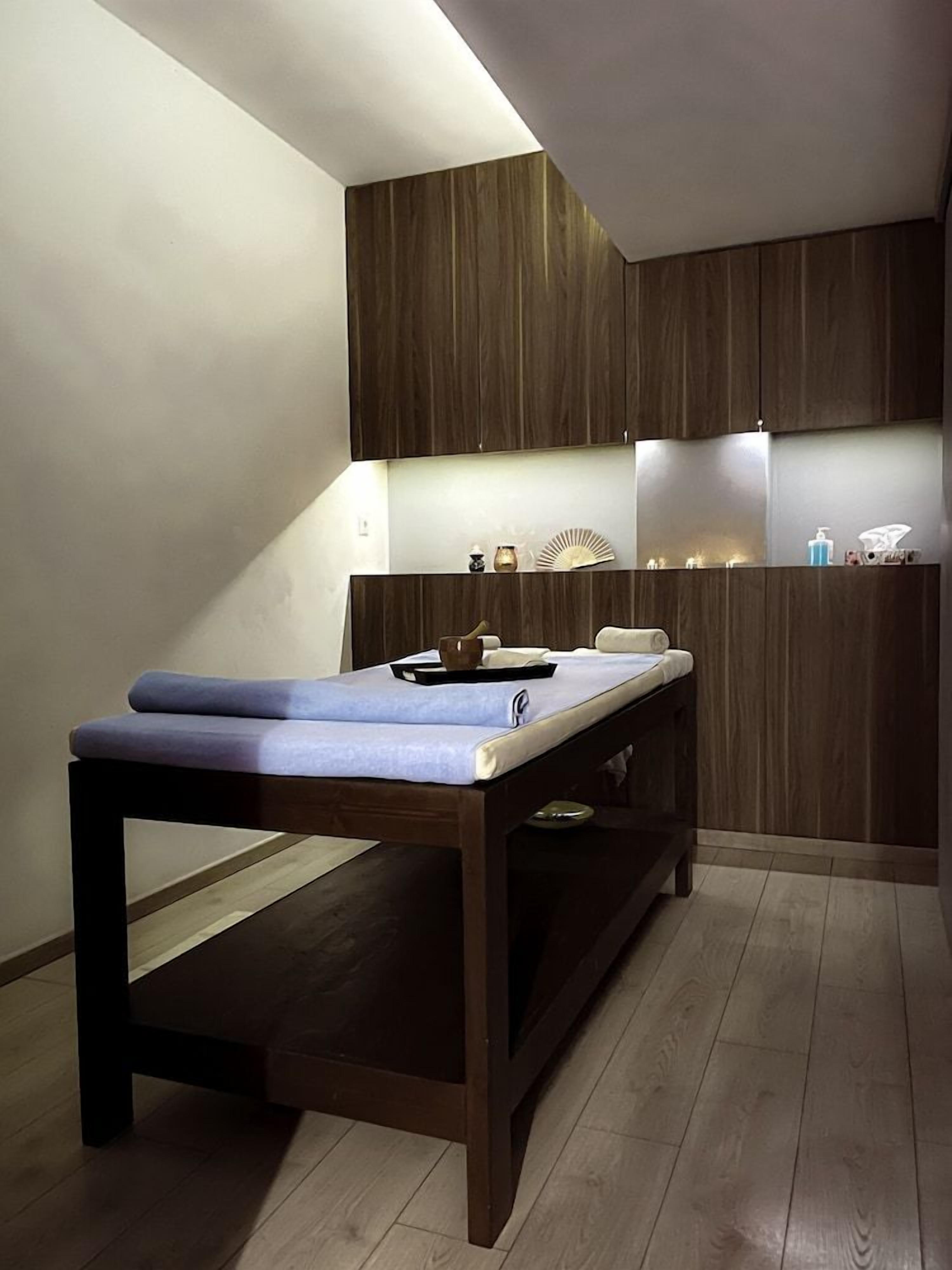 Ein modernes Zimmer mit einer hölzernen Bank, einem kleinen Tisch und einem an der Wand befestigten Regal mit verschiedenen Gegenständen.
