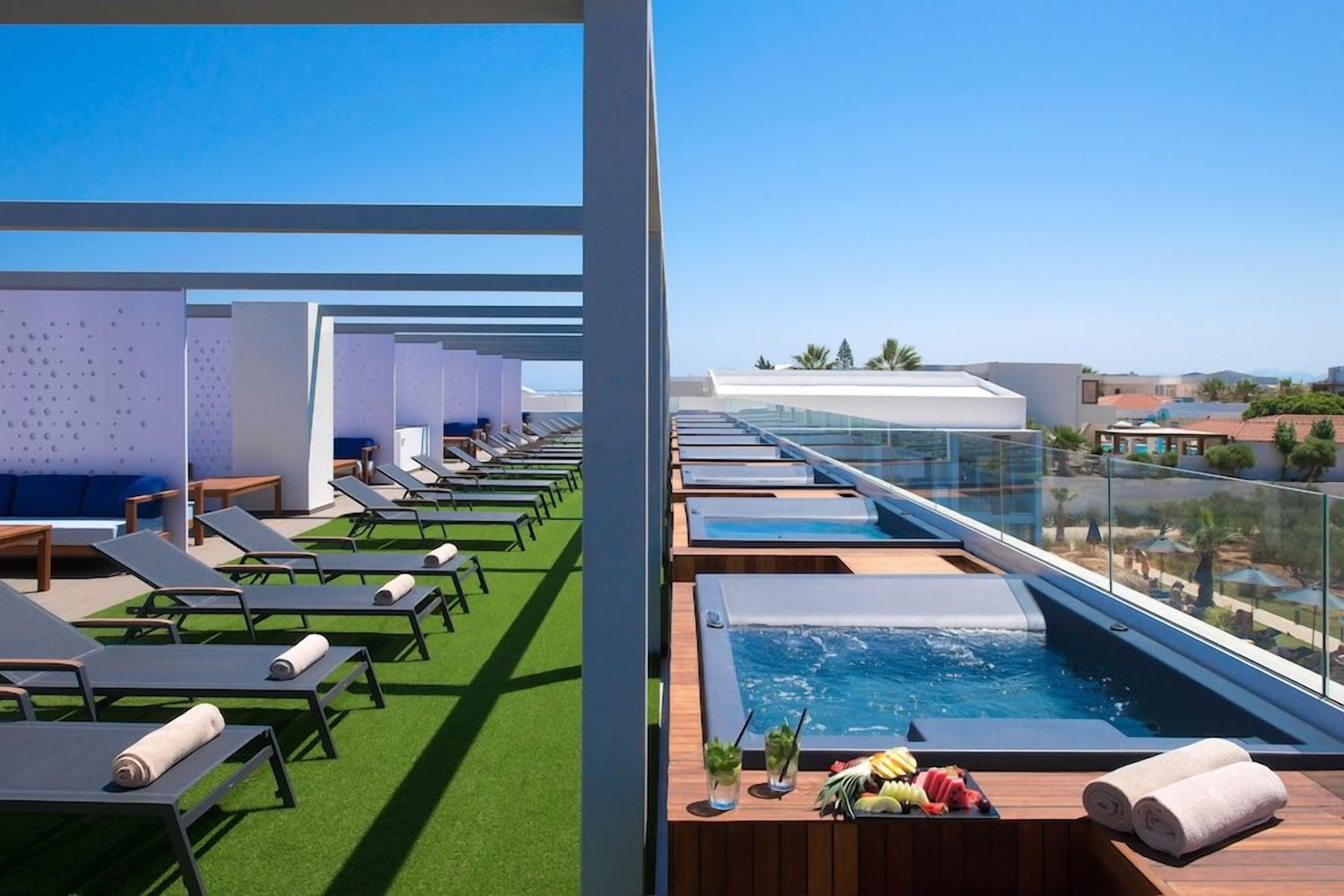 Una terraza en la azotea con sillones de sol, piscina y vistas de la ciudad.