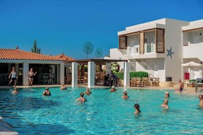 A swimming pool with people, a covered area, and a building with a star decoration. - Sensus Experience By Lavris Group (Hersonissos)