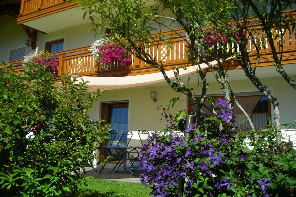 A hotel with a balcony, outdoor seating, and lush greenery.