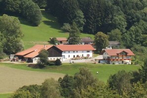 Um edifício grande com várias seções, cercado por campos verdes e árvores.