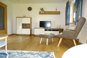 A living room with a television, a cabinet, a chair, and a small table. - Holiday apartment with 1 bedroom (Sankt Englmar)