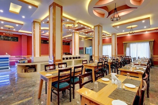 A restaurant with multiple dining tables, chairs, and a bar area. - Yashshree Sikkim Blossom (Gangtok)