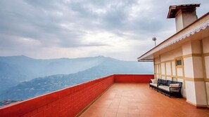 A terrace with a red wall and a view of distant mountains. - Yashshree Sikkim Blossom (Gangtok)