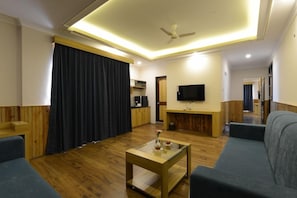 A modern living room with a sofa, a coffee table, a television, and a ceiling fan. - Yashshree Sikkim Blossom (Gangtok)