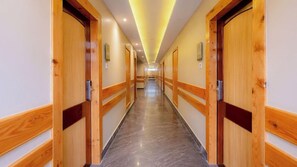 A hotel hallway with wooden doors, a marble floor, and a ceiling with recessed lighting. - Yashshree Sikkim Blossom (Gangtok)