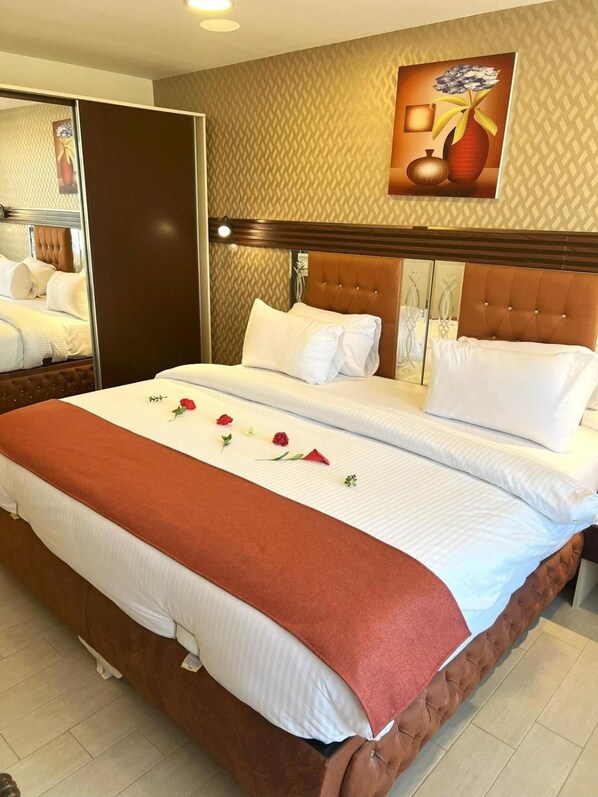 Quarto de hotel com uma cama grande, cabeceira de madeira e um espelho em uma das paredes.