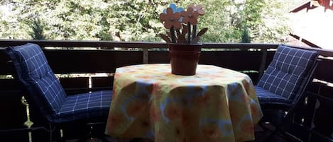 Un espace extérieur aménagé avec une table et des chaises, un pot de fleurs et une vue sur les arbres.