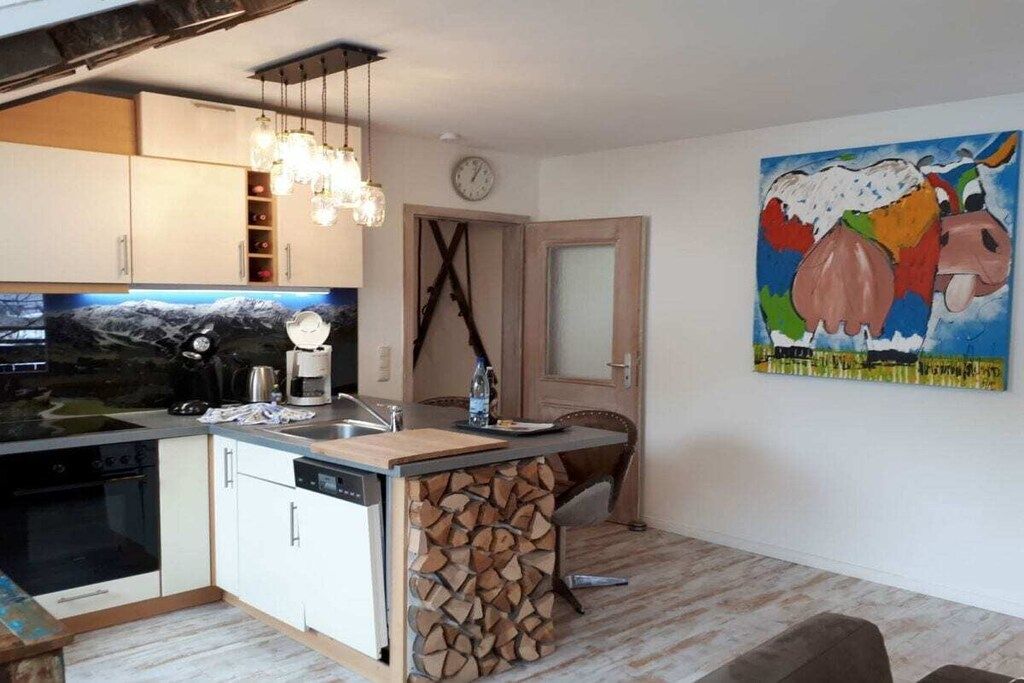 A kitchen with a built-in stove, a sink, and a wooden island with a stack of firewood.