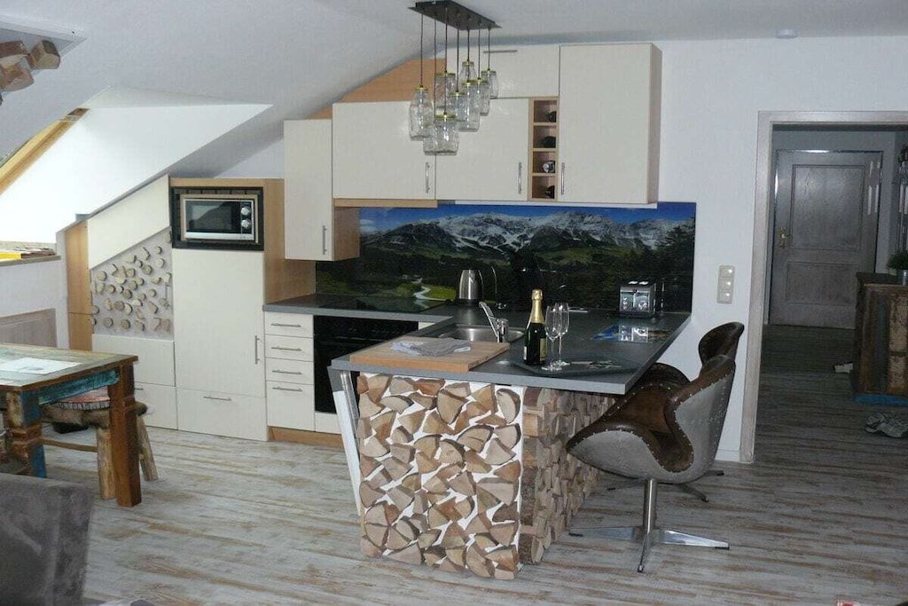 A kitchen with a built-in island, a microwave, and a painting of a mountain landscape.