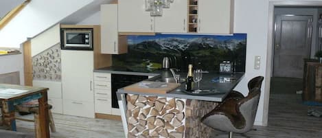 A kitchen with a built-in island, a microwave, and a painting of a mountain landscape.