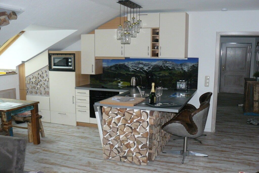 A kitchen with a built-in island, a microwave, and a painting of a mountain landscape.