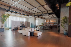 A spacious living area with a sectional sofa, a dining table, and a kitchen in the background. - Breakx Hotel Penang (George Town)