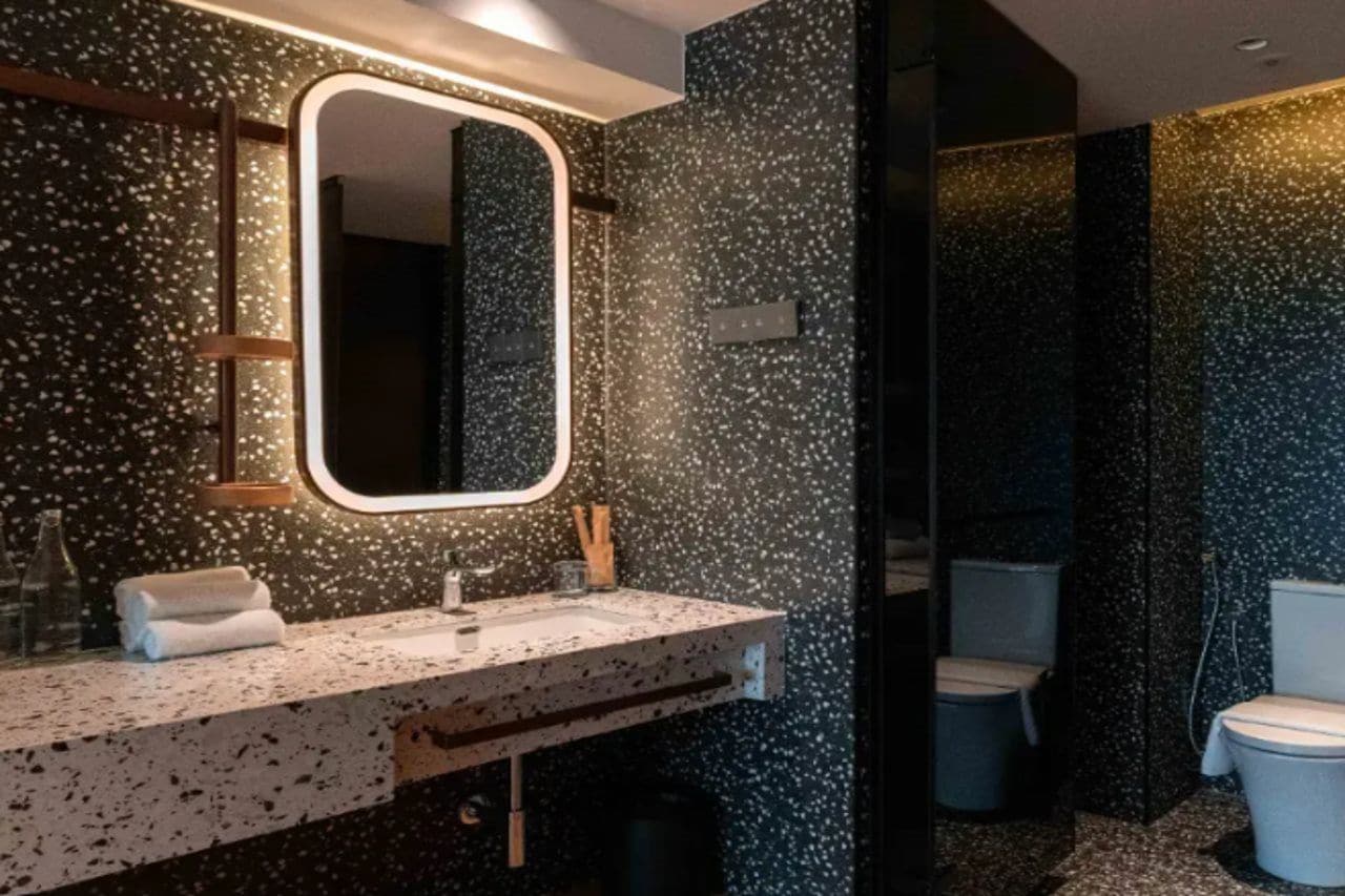 Een moderne badkamer met een spatborden met spikkels, een grote spiegel en een wastafel met twee kommen.