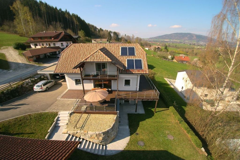 Una casa a due piani con tetto in tegole, un balcone e un vialetto lastricato.
