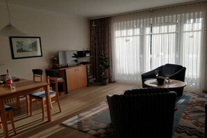 Ein Wohnzimmer mit Essbereich, einer Couch, einem Couchtisch und einem Fernseher.