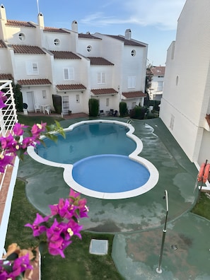 Un quartier résidentiel avec une piscine, des maisons blanches et un ciel dégagé.