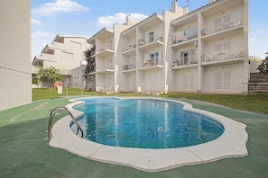 Ein Pool mit geschwungener Kante, umgeben von einer grünen Liegefläche.