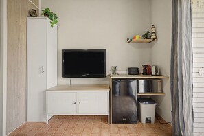 A compact kitchenette with a built-in TV, a mini-fridge, a coffee maker, and a trash bin.