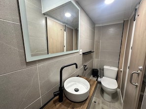Une salle de bain moderne avec un lavabo rond, des toilettes et un miroir au-dessus du lavabo.