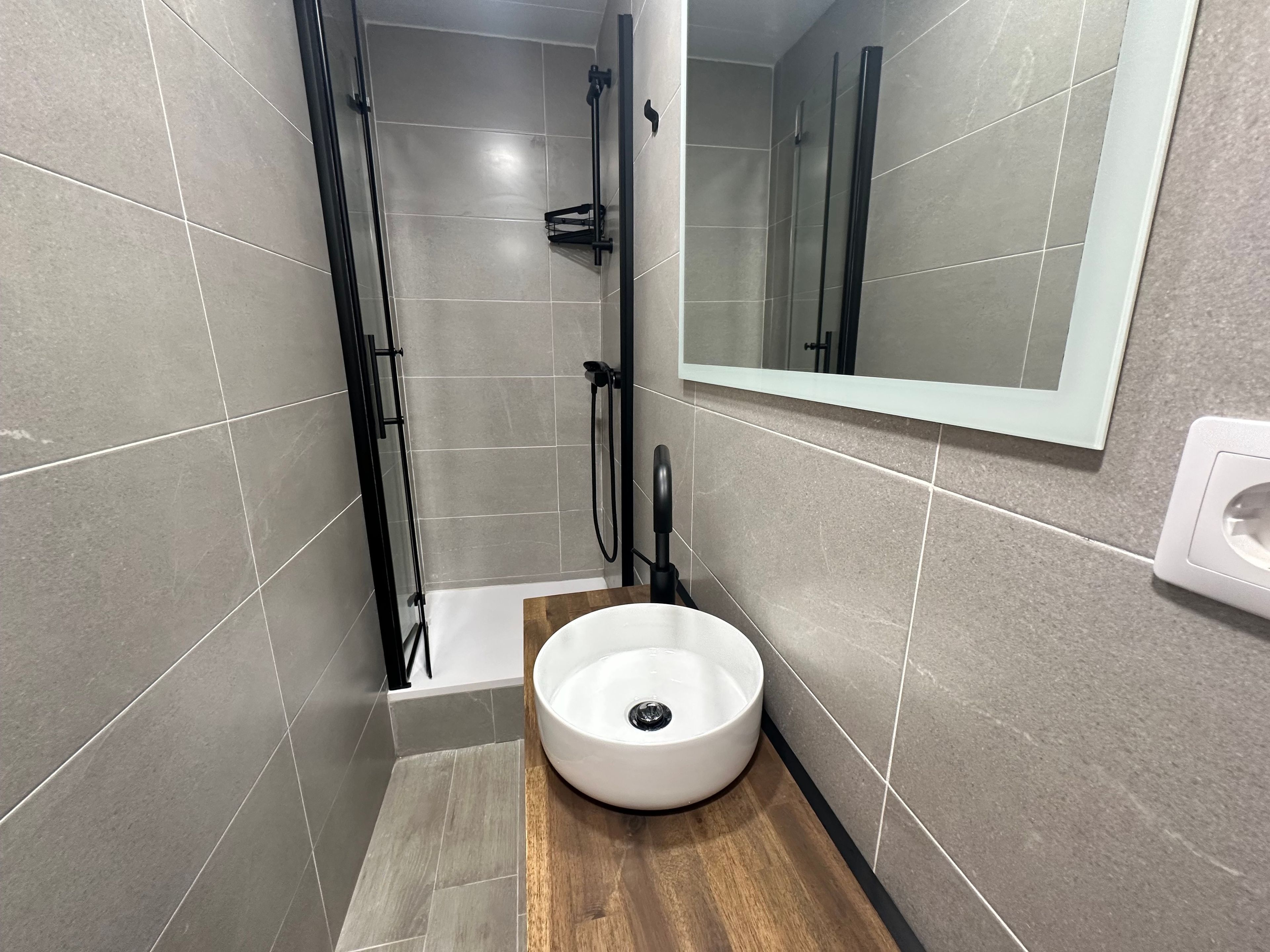 Une salle de bain moderne avec une douche, un lavabo et un miroir.