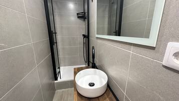 Une salle de bain moderne avec une douche, un lavabo et un miroir.