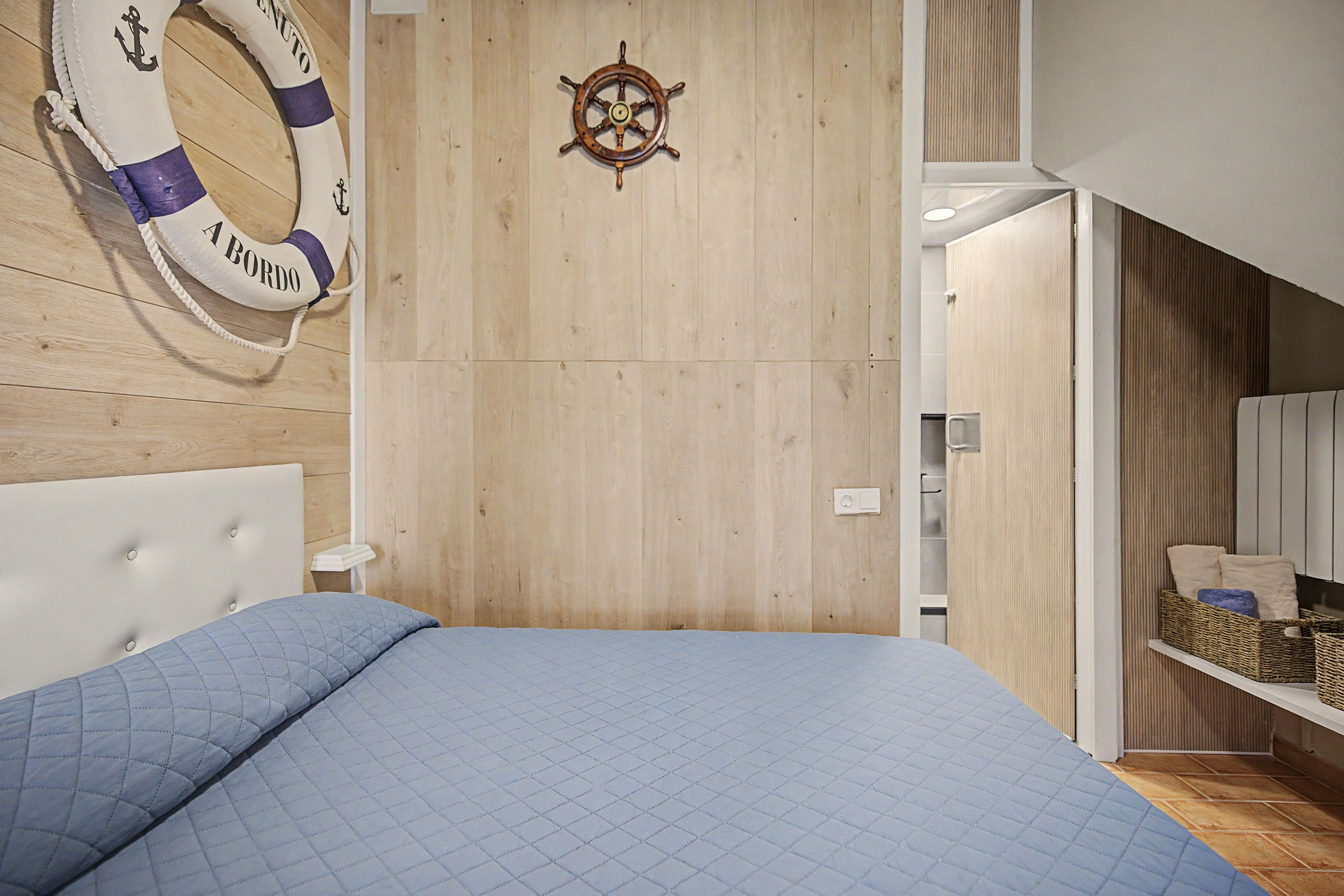 Ein Schlafzimmer mit einem Bett, einem Rettungsring und einem Schiffsrad an der Wand.